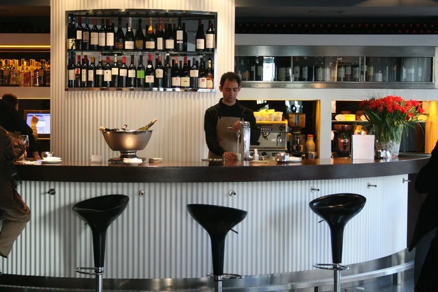 A round bar counter with stools and shelves of bottles behind it