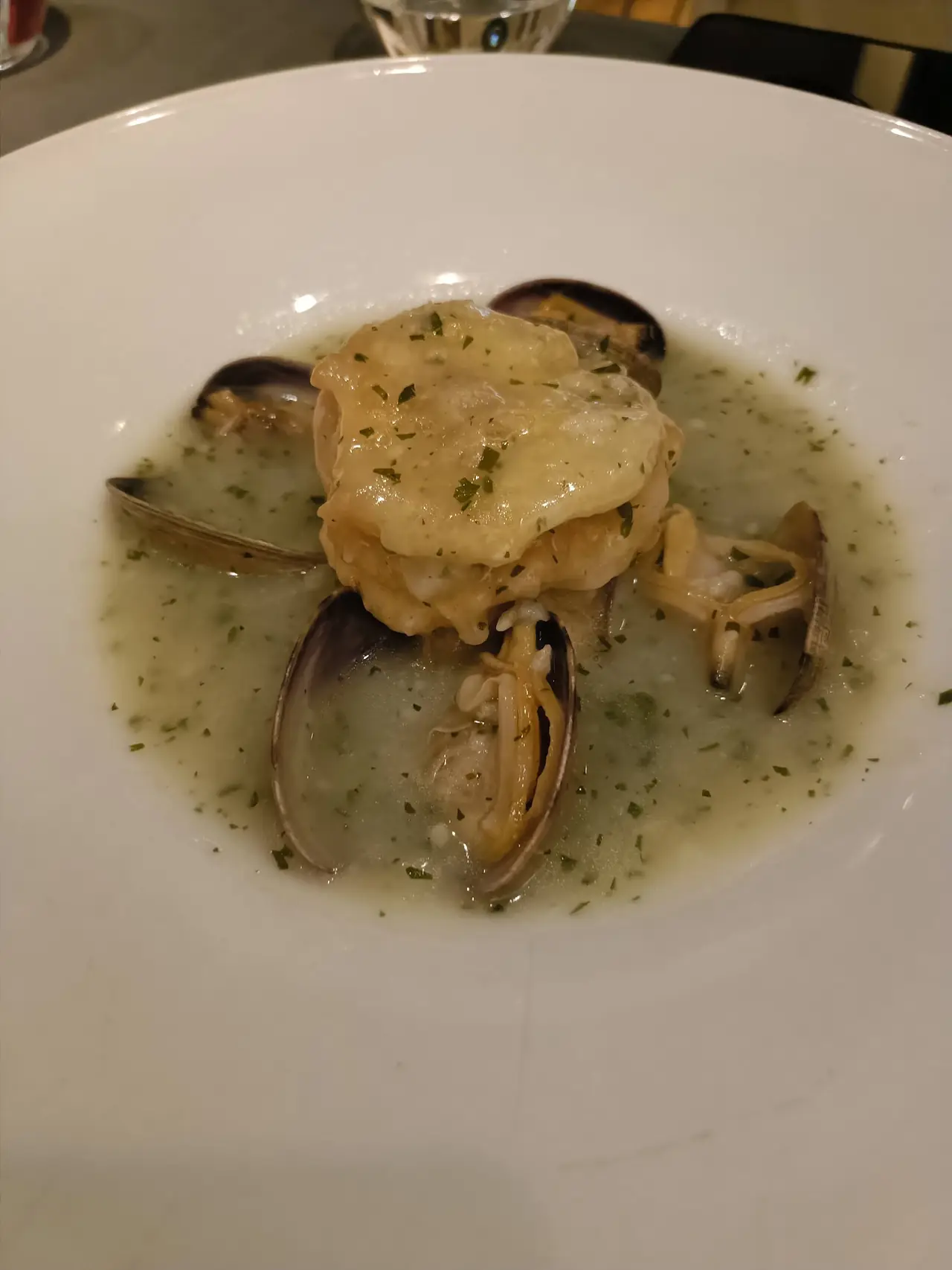 Fish fillet with clams in green herb broth in a bowl