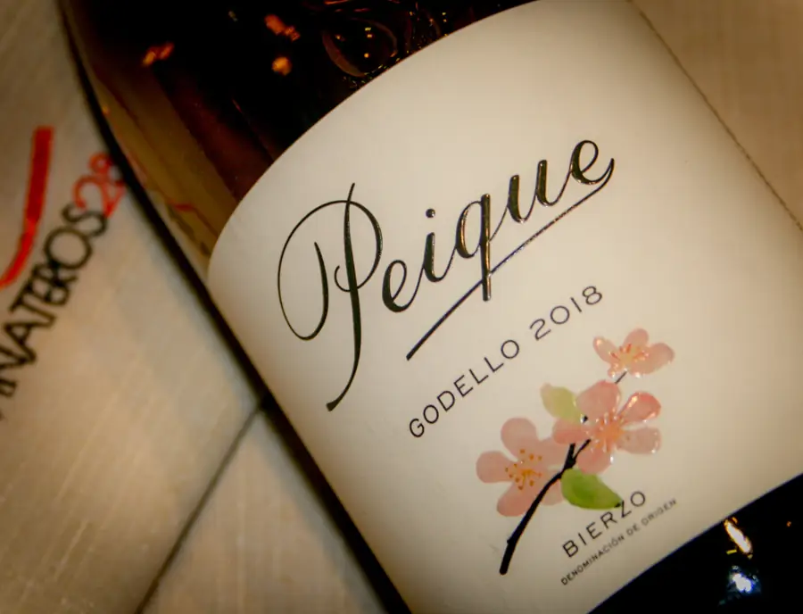 Close-up of a Peique Godello 2018 Bierzo white wine bottle resting on a Vinateros-branded surface