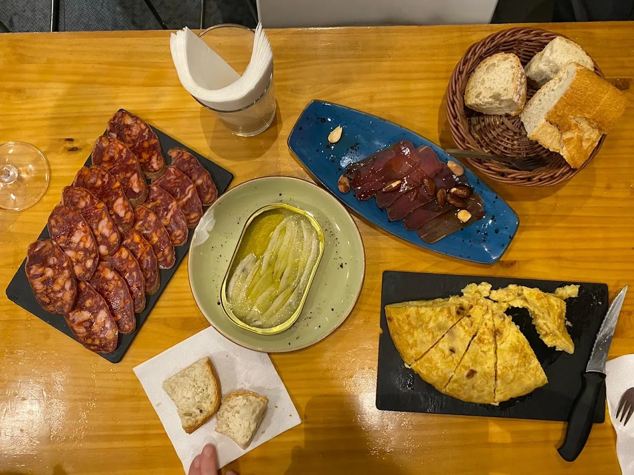 An overhead view of jamon, olives, cheese, and bread on a table