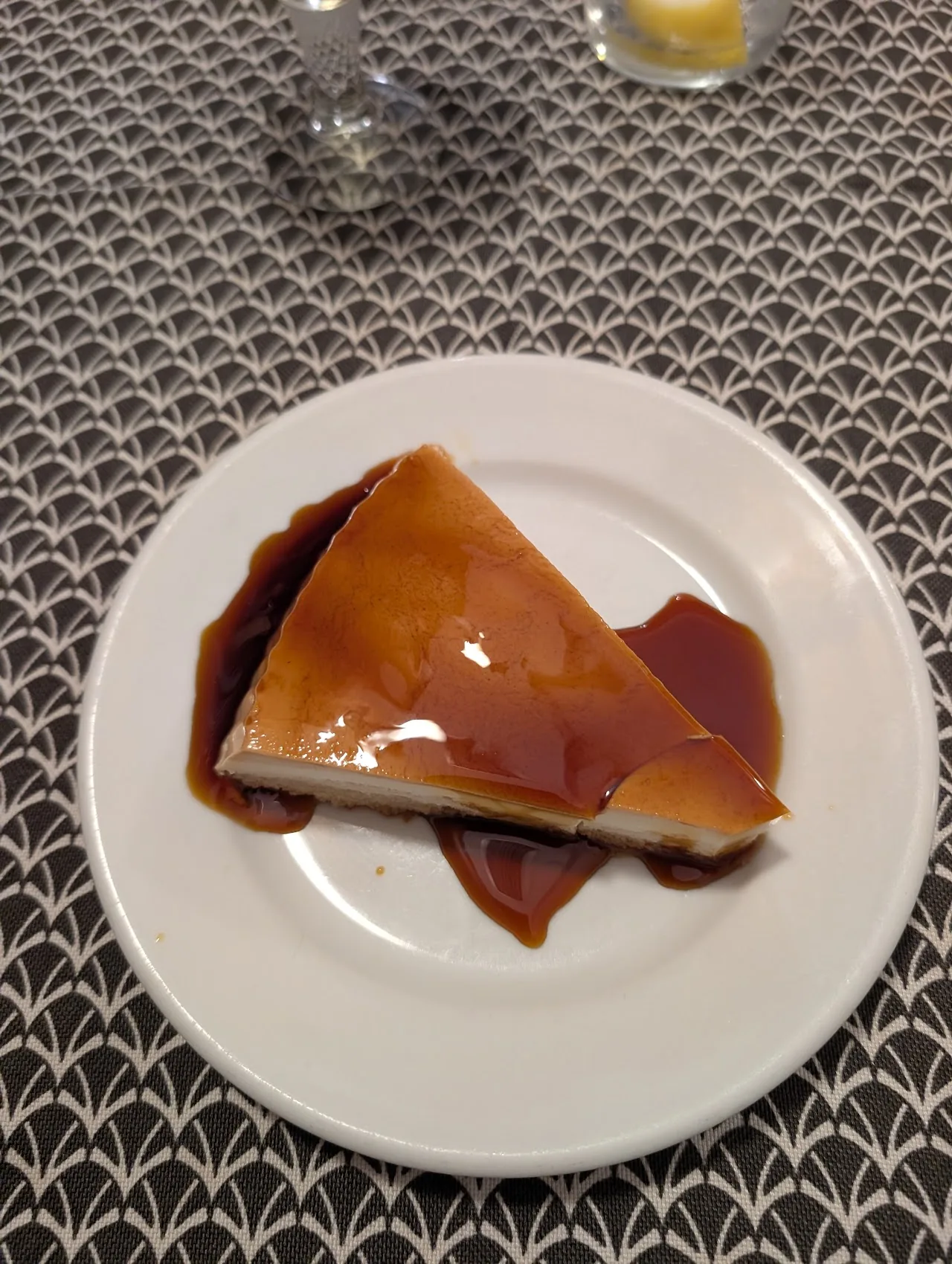 Overhead shot of a wedge-shaped dessert with a caramel glaze pooling on a white plate