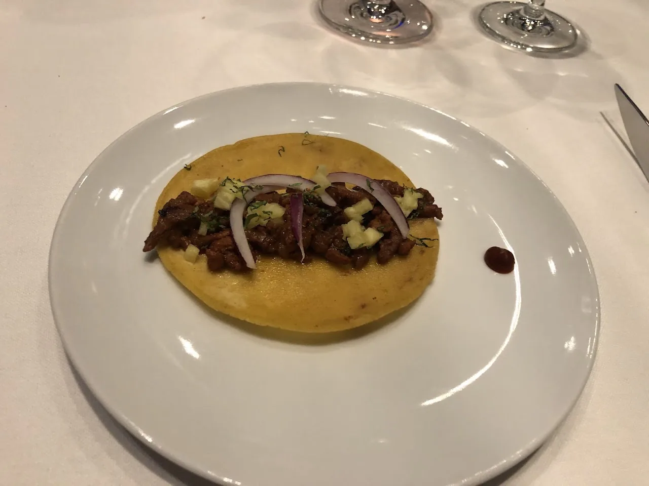 A row of thinly sliced ham and dried fruit canapes on a dark platter