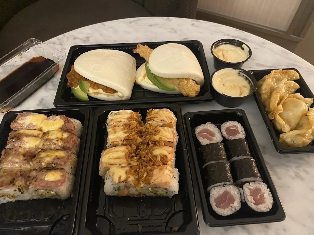 A platter of assorted sushi rolls, sandwiches, and dumplings