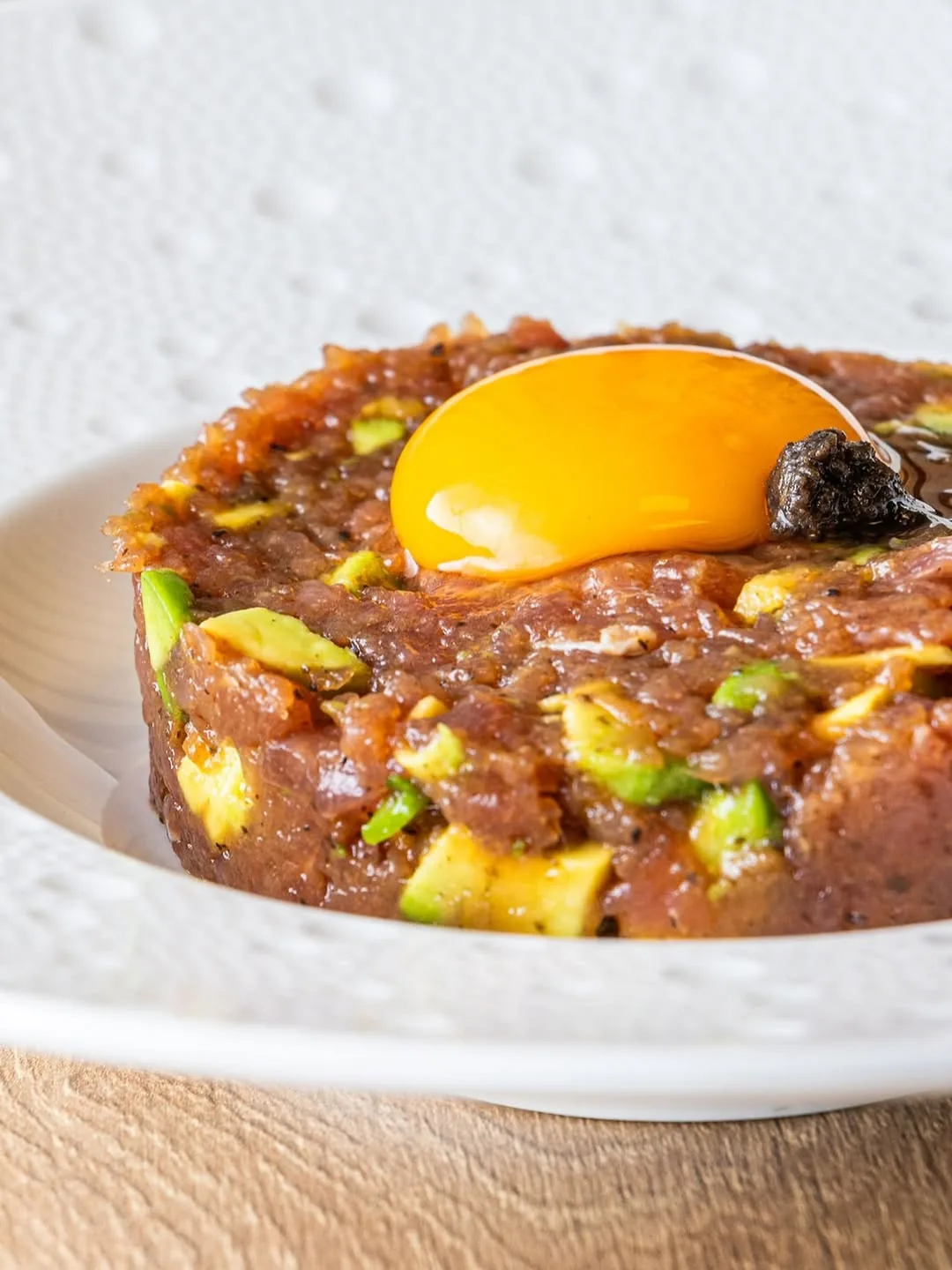Tuna tartare with avocado topped with a raw egg yolk