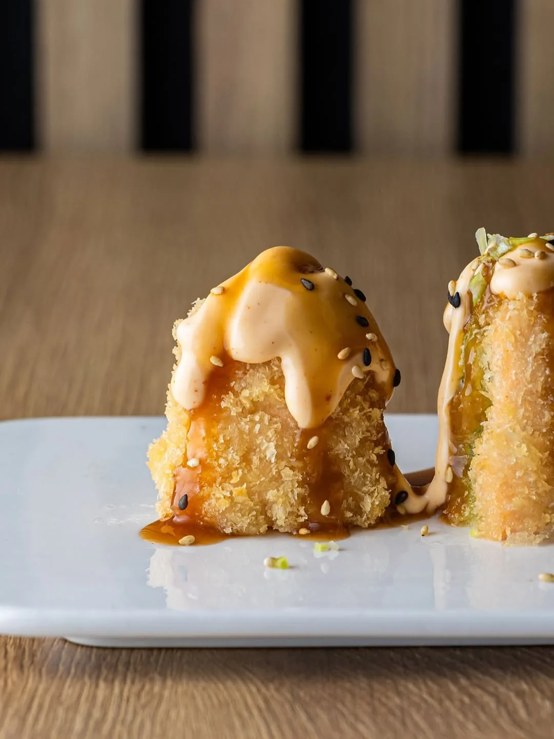 Crispy fried sushi roll topped with spicy sauce and sesame seeds