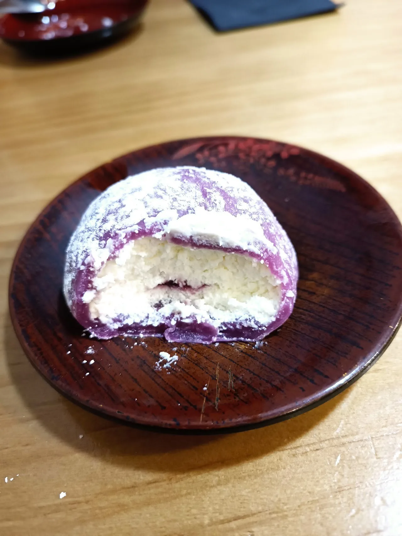 A white-dusted rice cake dessert on a dark red plate