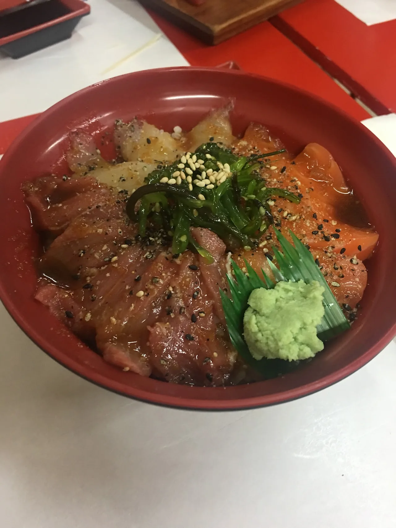 A poke bowl with tuna, seaweed salad, and wasabi