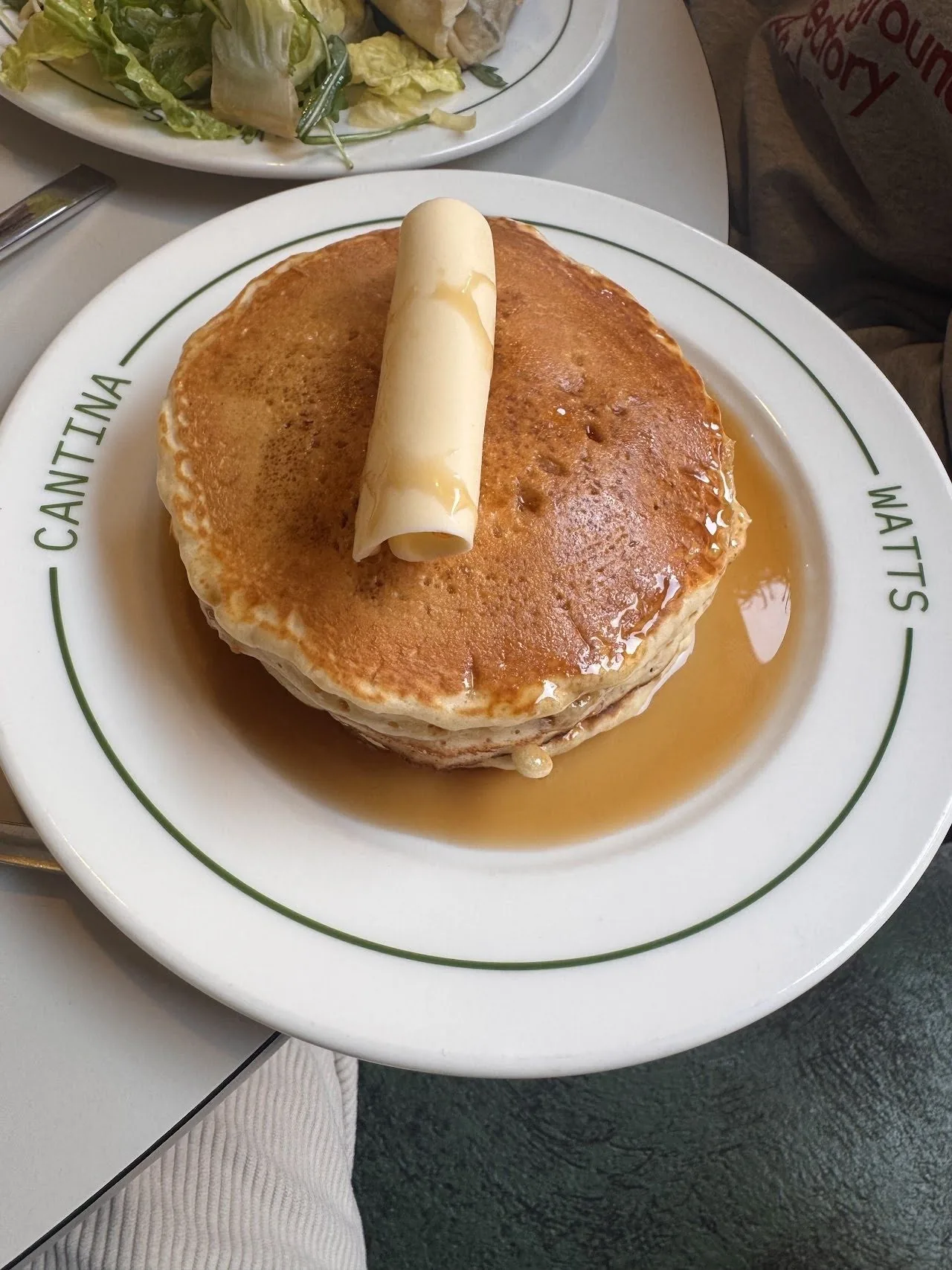 A stack of pancakes with a curl of butter on a white plate