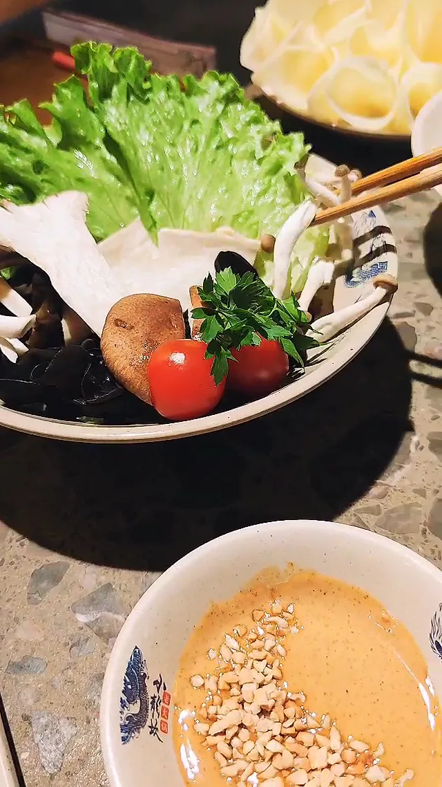 A platter of raw vegetables including lettuce, tomato, and potato, with dipping sauce