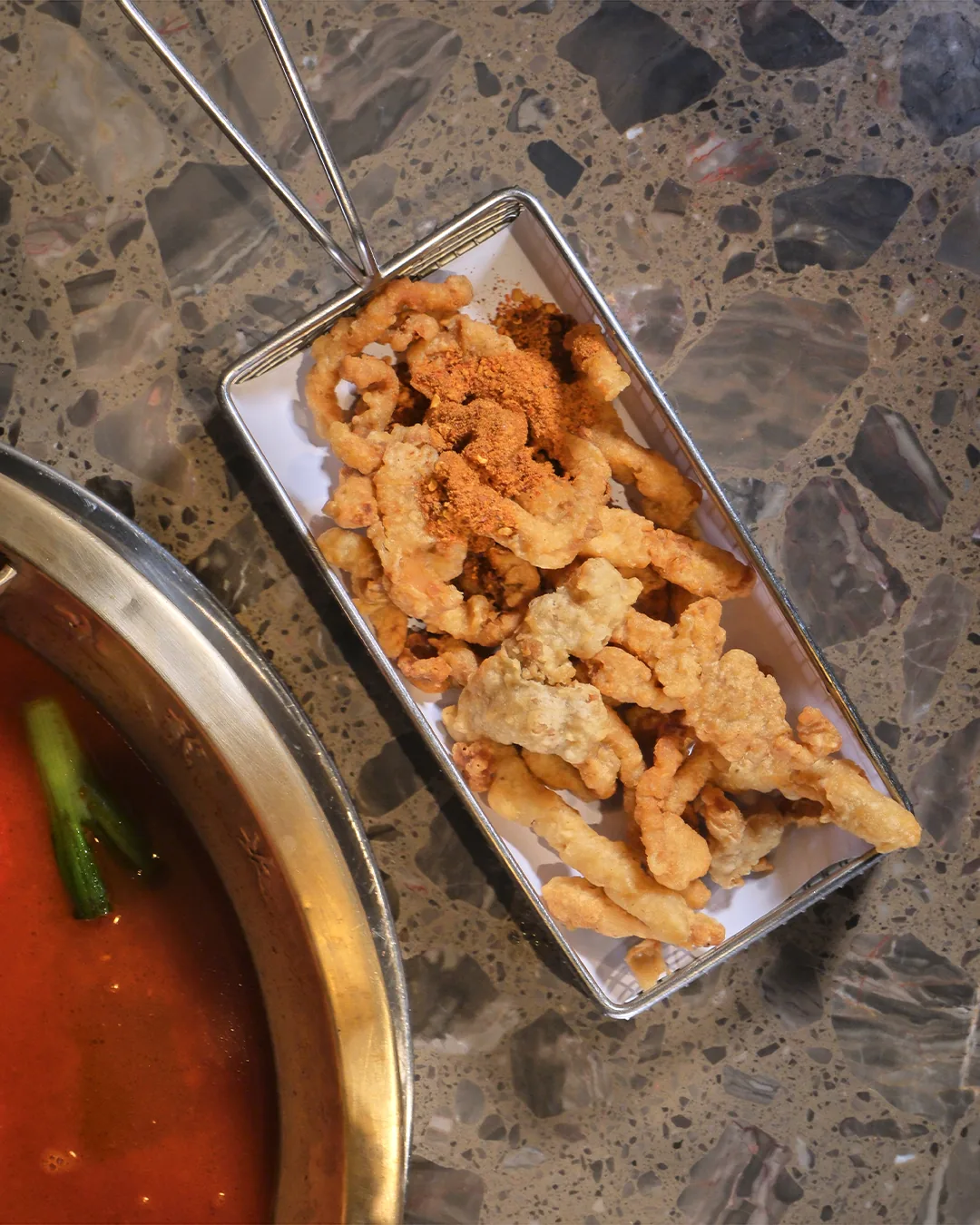 A tray of fried battered food beside a hot pot