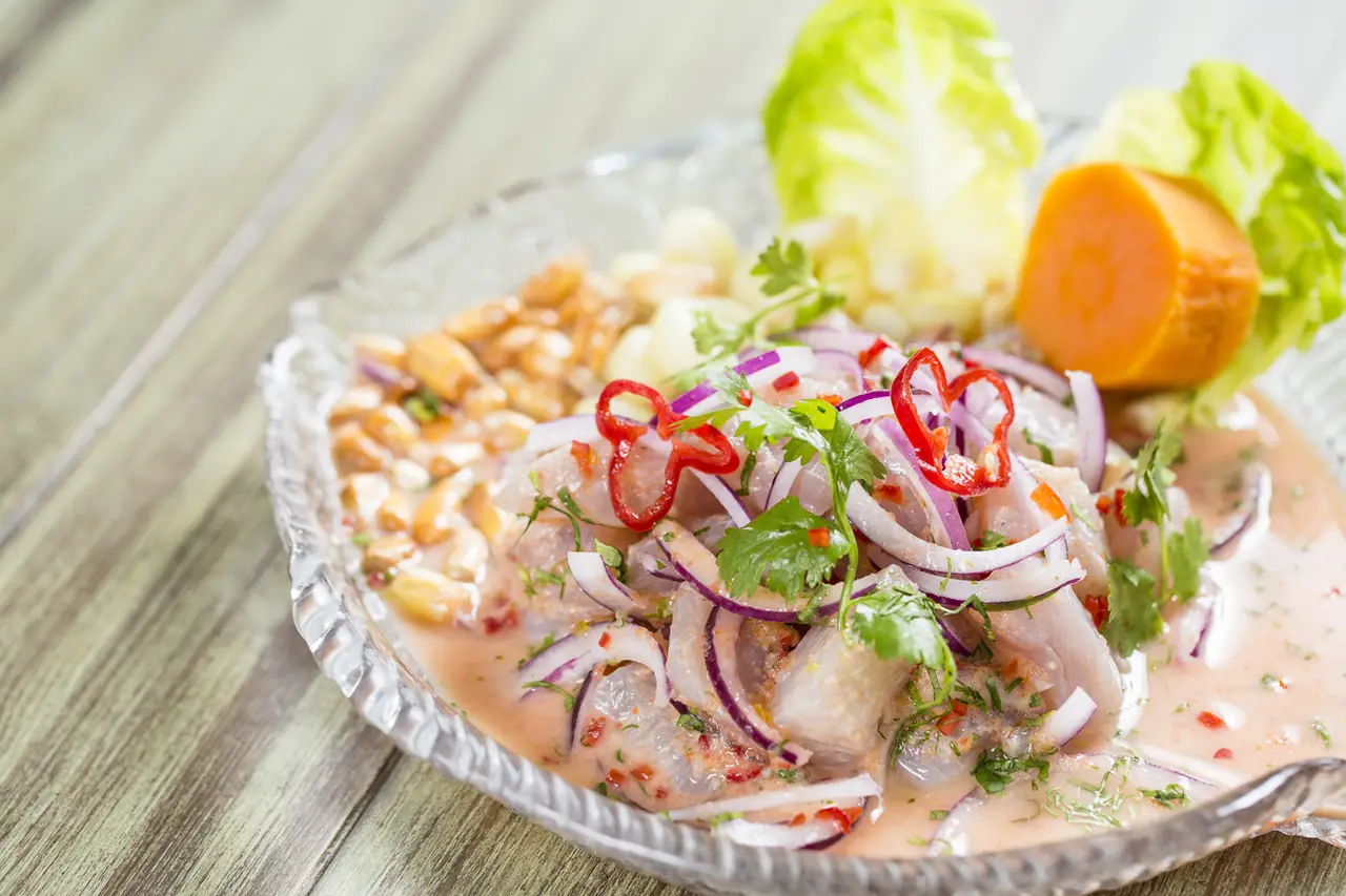 Peruvian ceviche with red onion, cilantro, chili slices, corn, and glass shrimp crackers, served with lettuce and sweet potato at Yakumanka