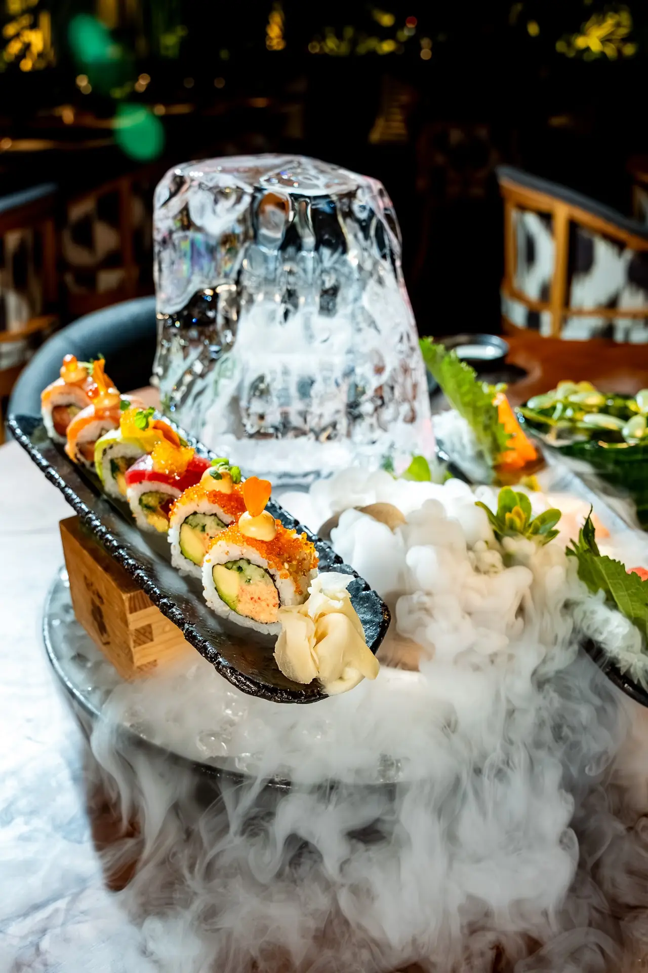 Sushi rolls plated beside a block of dry ice with smoke rising.