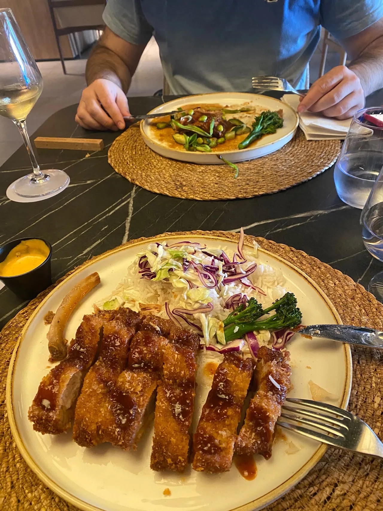 A sliced breaded cutlet over shredded purple cabbage slaw on a gold-rimmed plate