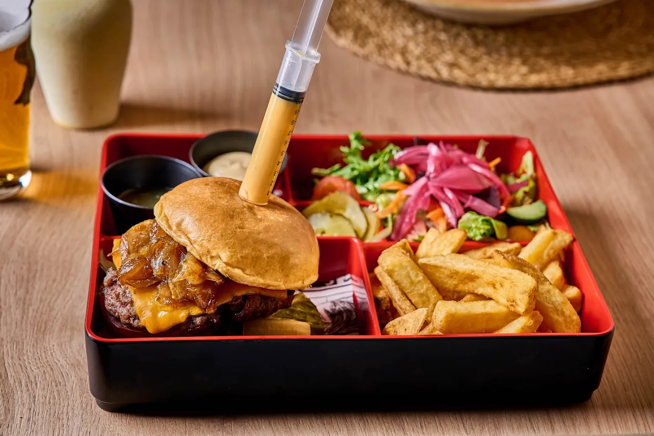 A bento box with a burger, fries, and a side salad