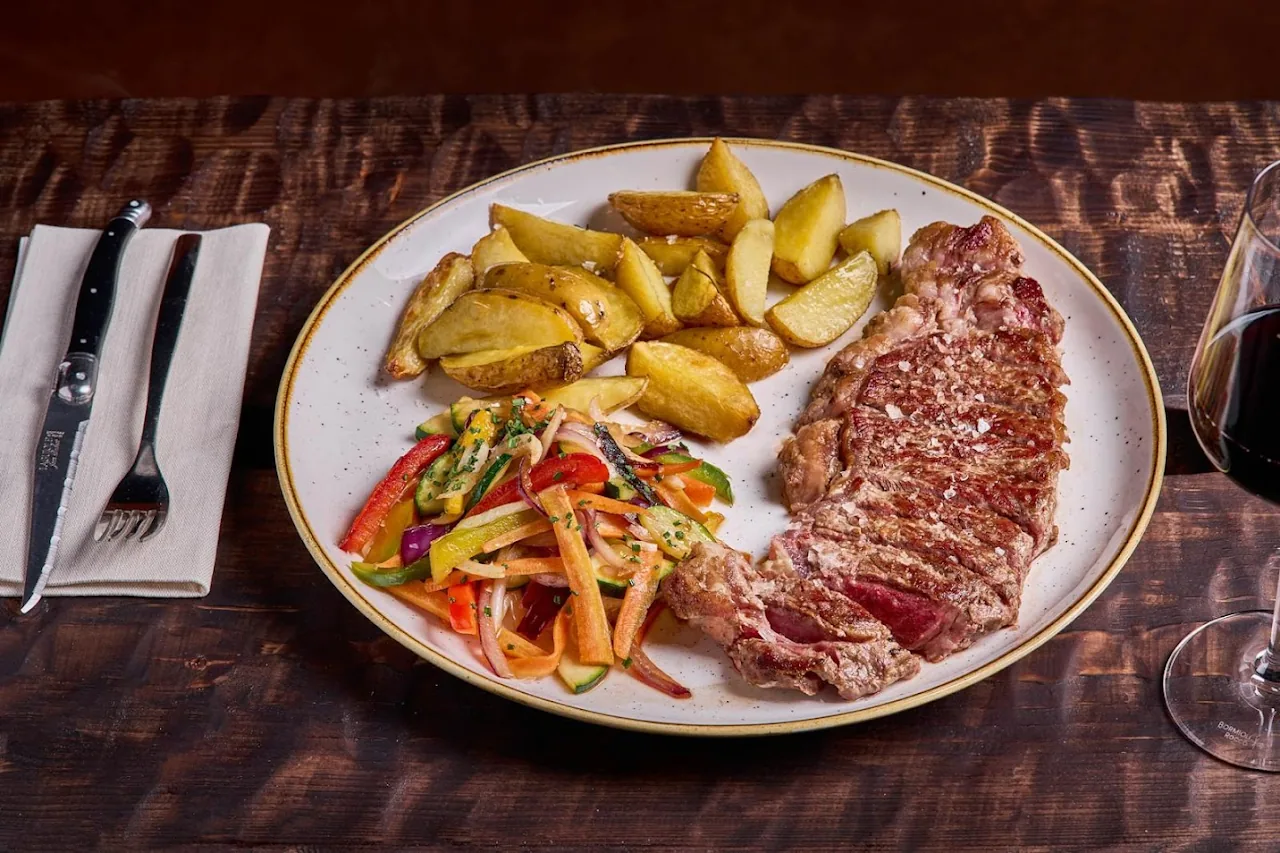 A sliced steak with roasted potato wedges and mixed vegetables on a plate