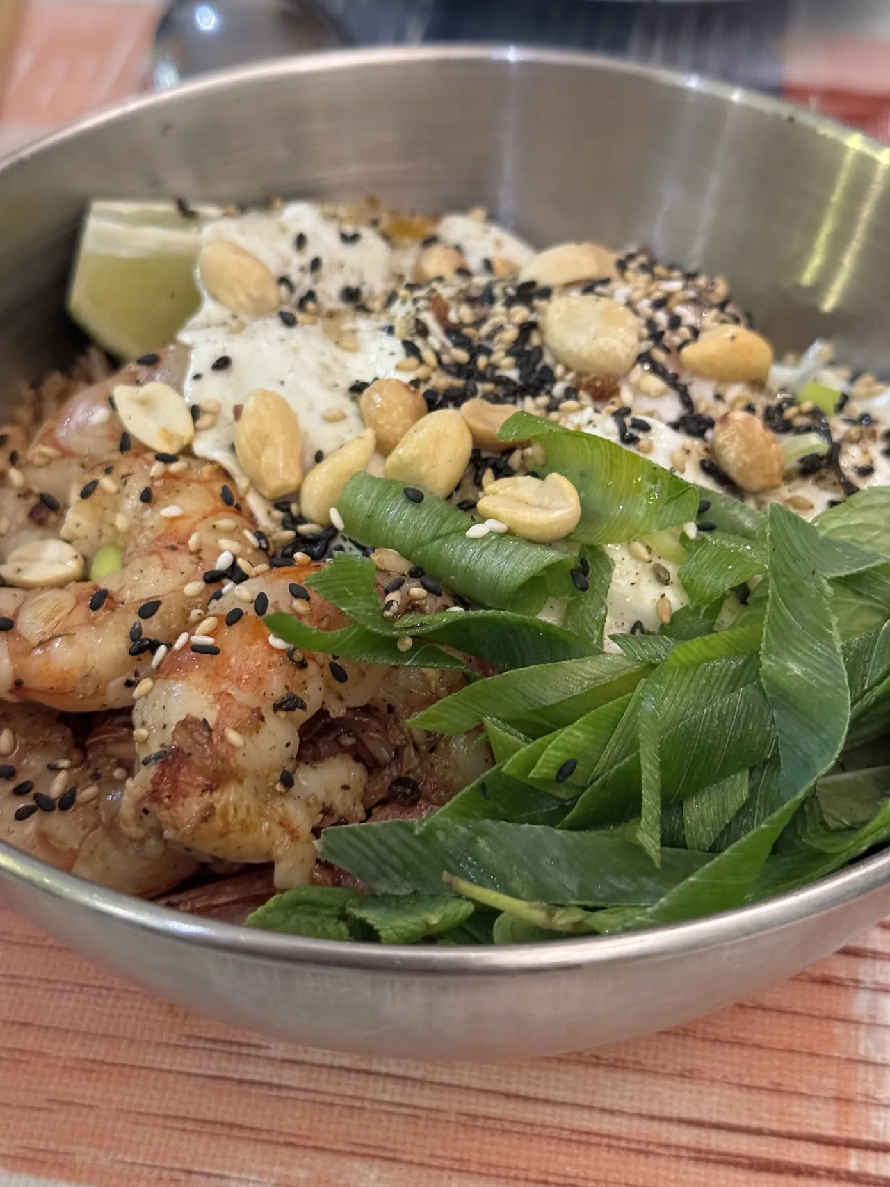 A bowl of shrimp with herbs, peanuts, and sesame seeds