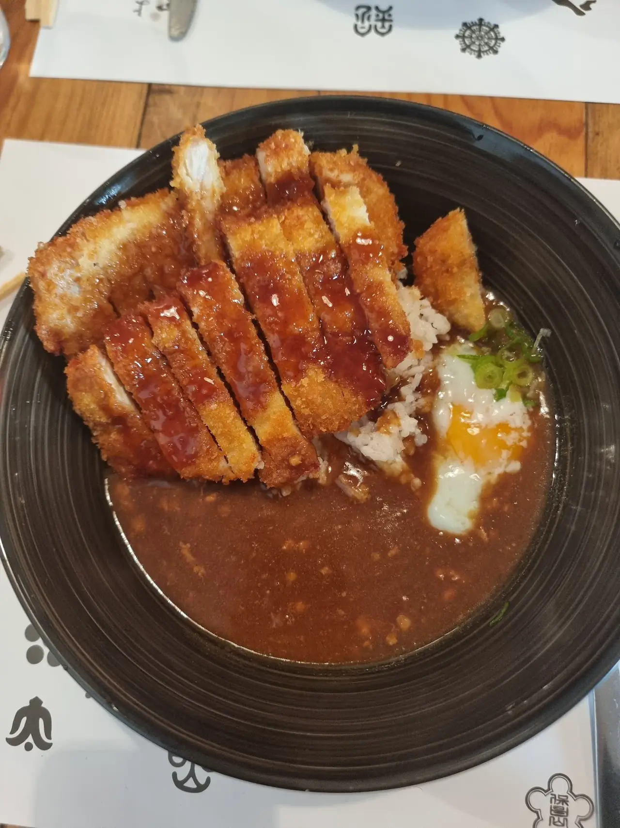 Katsu curry with sliced breaded pork cutlet over Japanese curry, rice and a soft egg, at Yoi Yoi Gion.