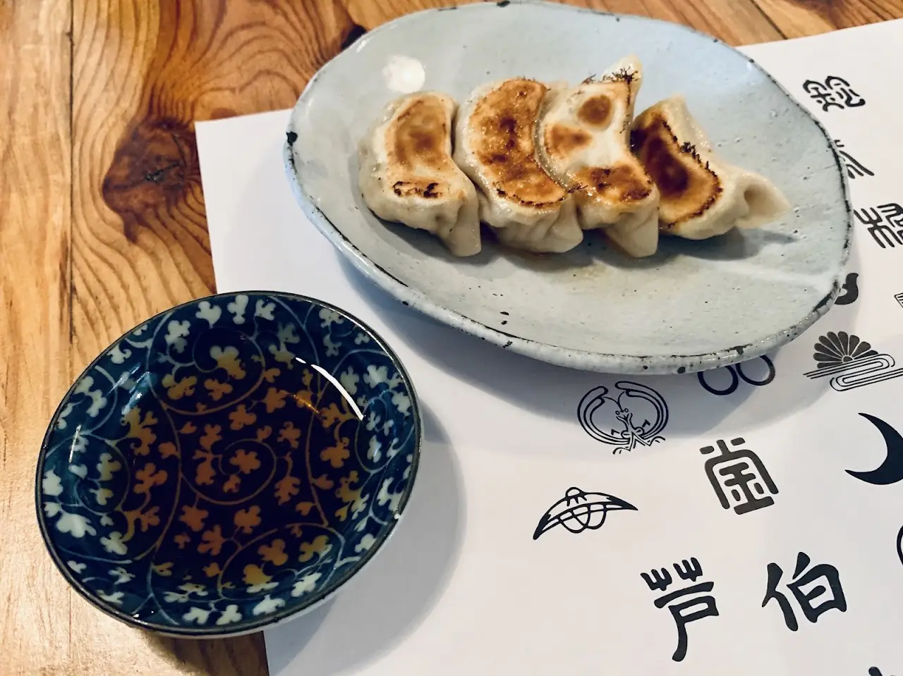 Plate of pan-fried gyoza dumplings with a dipping sauce, at Yoi Yoi Gion.