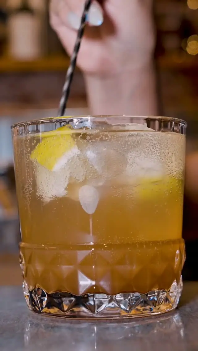 Amber cocktail with ice and citrus garnish in a cut-crystal glass