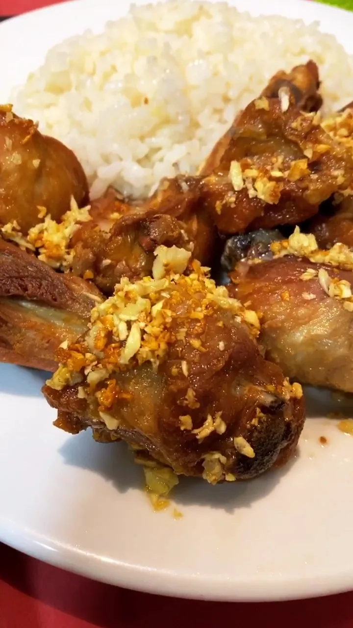 Fried chicken pieces with garlic bits over white rice