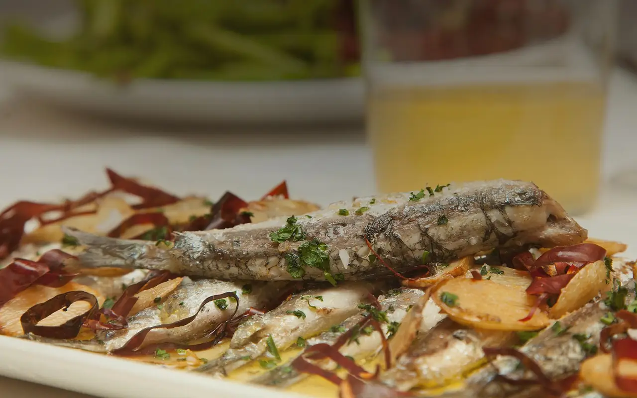 Grilled whole fish with sliced garlic, parsley and dried red pepper strips in olive oil