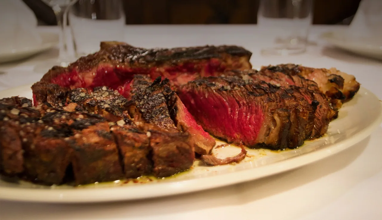 Sliced grilled steak with a pink centre on a white plate